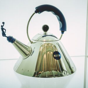 Close-up of a sleek Alessi kettle featuring a unique blue handle design.