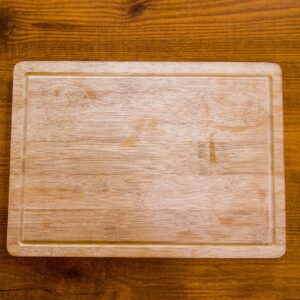 Top view of a natural wooden bamboo chopping board on a textured surface.