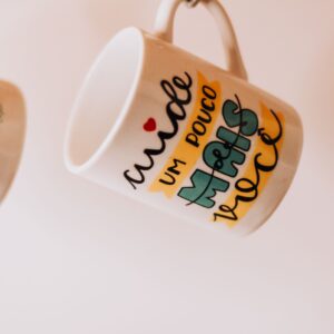 Colorful mugs with inspirational words in Portuguese displayed creatively.